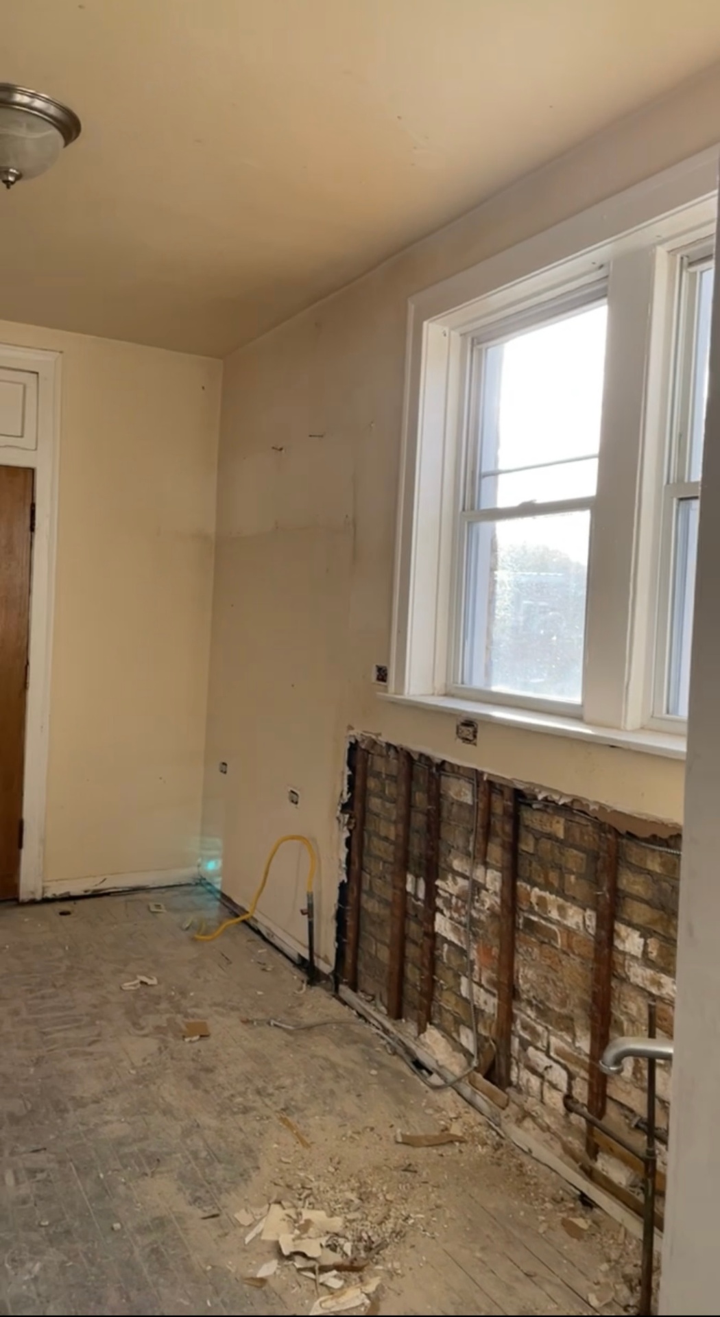 Kitchen wall with exposed brick and damaged plaster before drywall repair