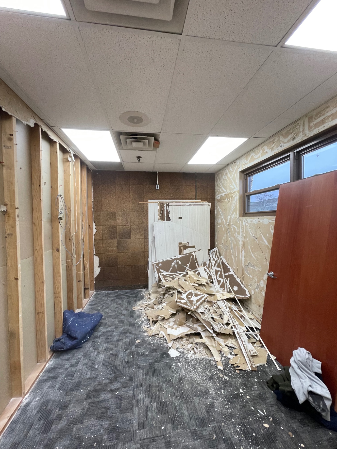 Commercial office stripped to studs with drywall debris piled on the floor before work by R&M Drywall