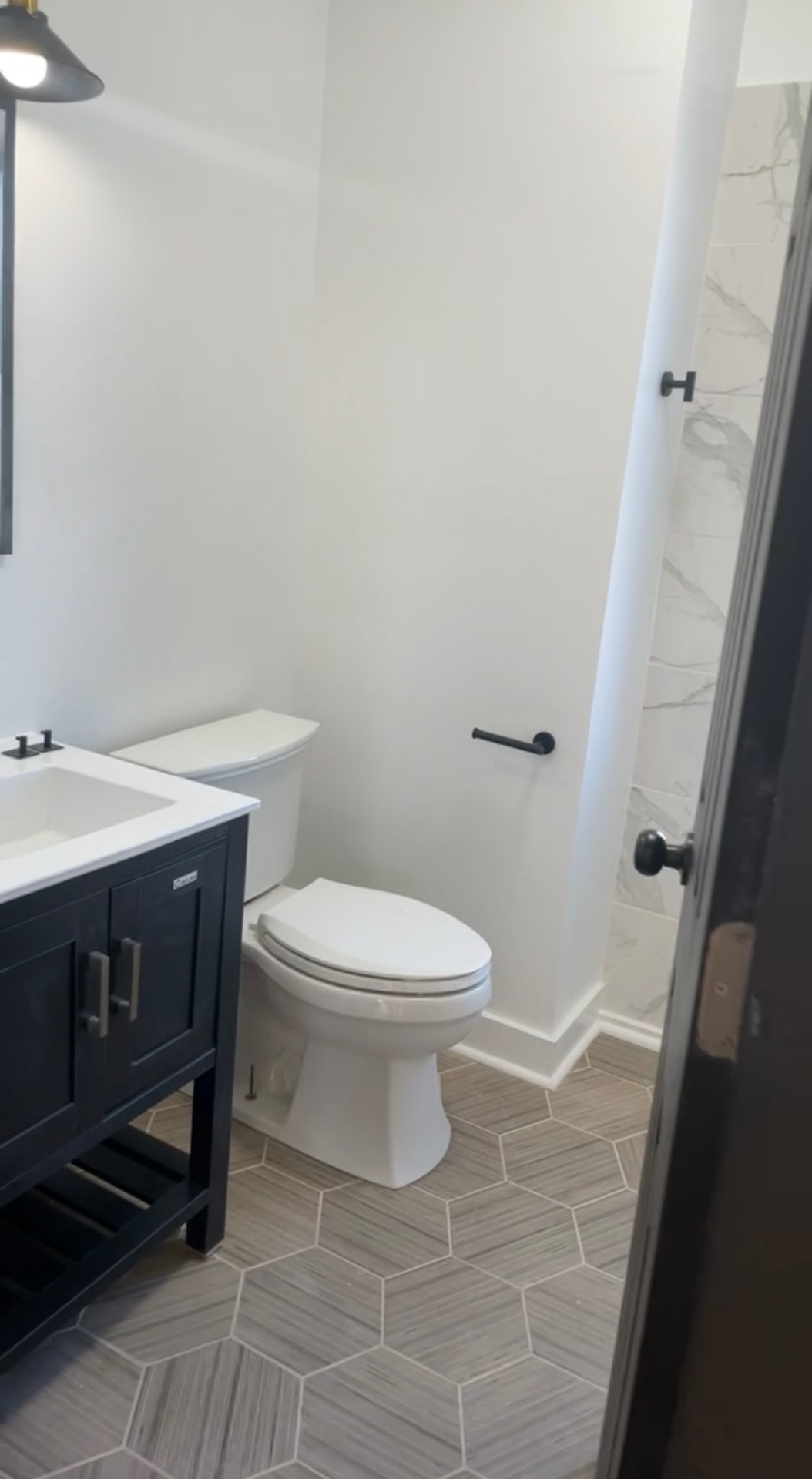Finished bathroom with clean white walls, baseboard and tile floor