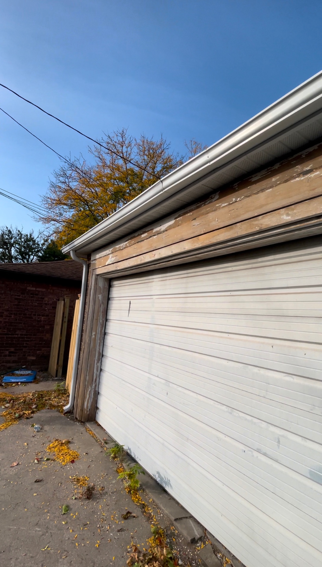 Garage exterior with weathered wood trim and faded door before R&M Drywall finishing work