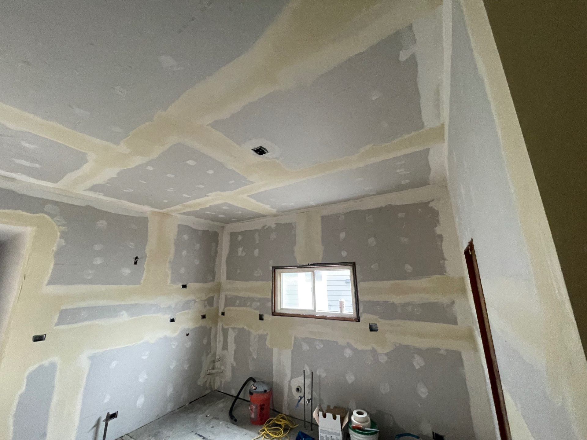 Ceiling and walls with joint compound applied over drywall seams and fastener spots